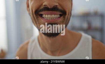 Hübscher junger Mann mit Bart, der drinnen in einem Wellness-Spa lächelt und in entspannter und beruhigender Atmosphäre helle, selbstbewusste Zähne zeigt Stockfoto