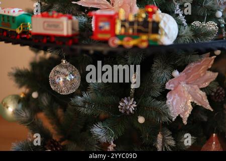 Ein wunderschön dekorierter Weihnachtsbaum mit einer lebendigen Spielzeugbahn und zahlreichen funkelnden Ornamenten Stockfoto