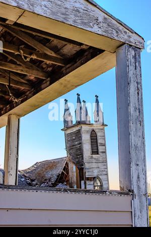 Ein Kirchturm mit vier Türmen ist von einer Veranda aus zu sehen. Das Gebäude scheint alt zu sein und muss repariert werden Stockfoto