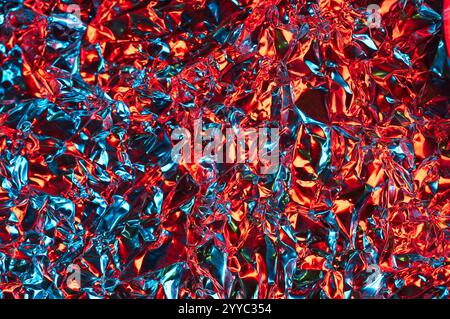 Strukturierter Abstract aus zerknitterter Aluminiumfolie mit reflektiertem farbigem Licht Stockfoto
