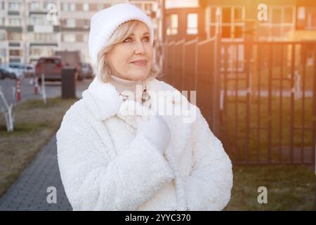 Lächelnde Seniorin in Winterkleidung, die in der Stadt spaziert Stockfoto