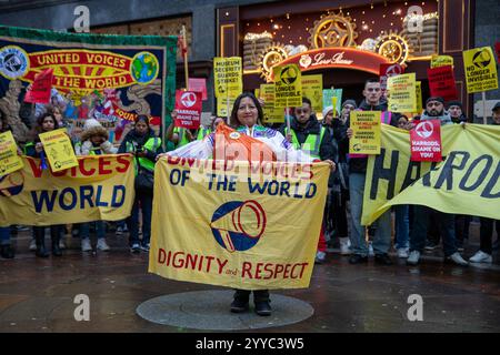 London, UK, 21. Dezember 2024. Demonstranten stehen hinter Protestbannern. Mitglieder der UVW union halten eine Demonstration vor dem weltberühmten Londoner Kaufhaus Harrods ab. Restaurantpersonal, Reinigungspersonal und Sicherheitsbeamte halten an einem der geschäftigsten Einkaufstage des Jahres eine Streikschlange vor dem Haupteingang. Die UVW-gewerkschaft fordert, dass ihren Mitgliedern ein versprochener Weihnachtsbonus, eine Erhöhung der Regellöhne und eine Verbesserung der allgemeinen Arbeitsbedingungen gezahlt wird. Quelle: James Willoughby/ALAMY Live News Stockfoto