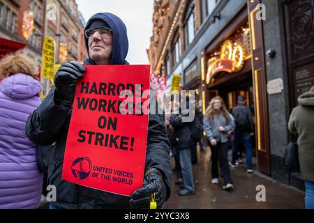 London, UK, 21. Dezember 2024. Ein Demonstrant hält ein Protestzeichen hoch. Mitglieder der UVW union halten eine Demonstration vor dem weltberühmten Londoner Kaufhaus Harrods ab. Restaurantpersonal, Reinigungspersonal und Sicherheitsbeamte halten an einem der geschäftigsten Einkaufstage des Jahres eine Streikschlange vor dem Haupteingang. Die UVW-gewerkschaft fordert, dass ihren Mitgliedern ein versprochener Weihnachtsbonus, eine Erhöhung der Regellöhne und eine Verbesserung der allgemeinen Arbeitsbedingungen gezahlt wird. Quelle: James Willoughby/ALAMY Live News Stockfoto