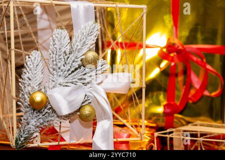 Die raffinierte Weihnachtsdekoration zeigt einen Holzrahmen, der mit Tannenzweigen, Ornamenten und Bändern in der Nähe wunderschön gewickelter Geschenke verziert ist und eine warme Atmosphäre schafft Stockfoto