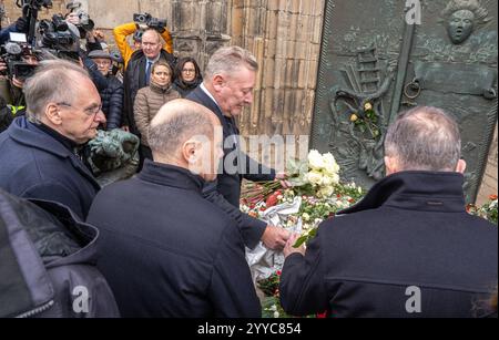 Nach dem gestrigen Anschlag auf den Magdeburger Weihnachtsmarkt legt am Samstag 21.12.2024 Bundeskanzler Olaf Scholz SPD, Mitte, Volker Wissing parteilos, re., Bundesminister für digitale und Verkehr und Sachsen-Anhalts Ministerpraesident reiner Haseloff CDU, li., Kraenze am Eingang der St.-Johannis-Kirche in Magdeburg nieder. Auf den Weihnachtsmarkt in der Innenstadt von Magdeburg ist am Freitagabend 20.12.2024 ein mutmasslicher Anschlag veruebt worden. Ein Auto war in die Menschenmenge auf dem Weihnachtsmarkt gerast. Laute Polizei fuhr der Taeter mindestens 400 Meter über den Weihnachtsm Stockfoto