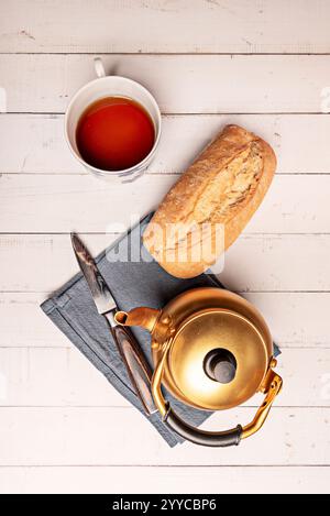 Eine goldfarbene Teekanne aus Aluminium mit einer Porzellanpfanne und einer Tasse Stockfoto
