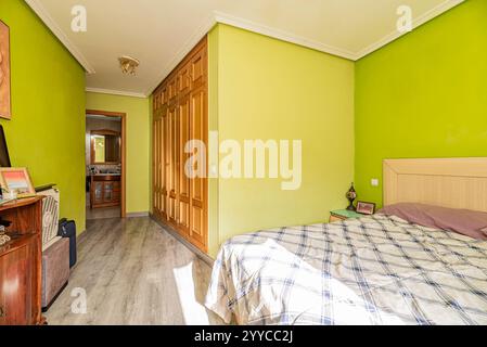 Eingangshalle zu einem Schlafzimmer mit Doppelbett mit pistaziengrünen Wänden und einem großen Einbauschrank mit Eichentüren und eigenem Bad Stockfoto