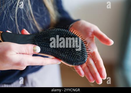 Eine junge Frau, die sich die Haare putzt und viele Haarausfall auf dem Kamm hat Stockfoto