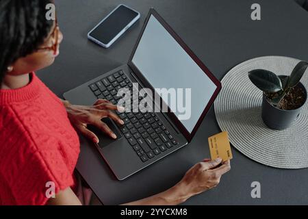Hochwinkelaufnahme einer nicht erkennbaren Frau, die beim Online-Shopping das Touchpad verwendet und eine Kreditkarte hält Stockfoto