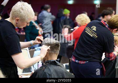 Berlin, Deutschland. Dezember 2024. Friseure schneiden bedürftigen und obdachlosen Menschen die Haare. Frank Zanders 30. Weihnachtsfeier für Obdachlose findet heute im Hotel Estrel statt. Annette Riedl/dpa/Alamy Live News Stockfoto