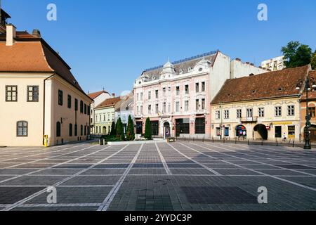 BRASOV (RUMÄNIEN) - der Ratsplatz (Piața Sfatului) in Brașov ist ein pulsierendes historisches Zentrum, umgeben von farbenfrohen Gebäuden und der berühmten Schwarzen Kirche, Stockfoto