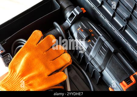 Draufsicht auf Bohrhammer, Werkzeugkasten, Handschuhe. Arbeitswerkzeuge, Worker Gear Concept. Nahaufnahme Stockfoto