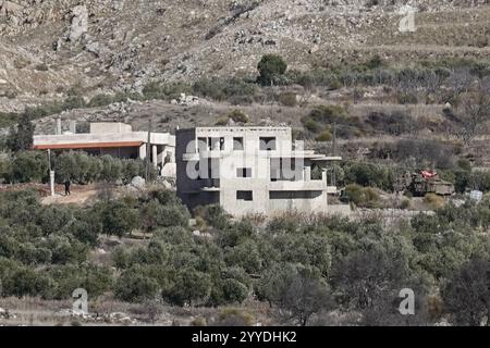 Majdal Shams, Israel. Dezember 2024. Panzerfahrzeuge der IDF werden (rechts) im syrischen Dorf Hader östlich der Grenze vom Drusendorf Majdal Shams aus gesehen, das sich in den israelisch kontrollierten Golanhöhen befindet. Quelle: Nir Alon/Alamy Live News Stockfoto