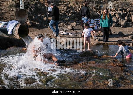 Merom Golan, Israel. Dezember 2024. Nachdem die Feindseligkeiten seit dem Waffenstillstandsabkommen zwischen Israel und dem Libanon am 27. November 2024 nachlassen, gehen die Israelis nach einer einjährigen Pause erneut nach draußen auf die Golanhöhen. Das Bental Reservoir wird von einer Grundwasserleitung gespeist, die von den Bauern in der Region in der Nähe des Kibbutz Merom Golan genutzt wird. Das Wasser stammt aus dem Shamir Drilling Project im Hula Valley, das eine unterirdische hydrothermale Quelle freilegte. Quelle: Nir Alon/Alamy Live News Stockfoto