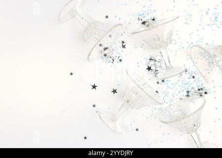Kleine Kristallgläser und Sternenkonfetti auf einem silberfarbenen glitzernden Hintergrund. Platz für Ihr Design. Stockfoto