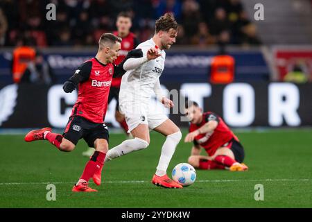 Leverkusen, Deutschland. Dezember 2024. Fußball: Bundesliga, Bayer Leverkusen - SC Freiburg, Spieltag 15, BayArena. Leverkusens Álex Grimaldo (l) und Freiburger Lucas Höler kämpfen um den Ball. Hinweis: Marius Becker/dpa - WICHTIGER HINWEIS: Gemäß den Vorschriften der DFL Deutschen Fußball-Liga und des DFB Deutschen Fußball-Bundes ist es verboten, im Stadion und/oder des Spiels aufgenommene Fotografien in Form von sequenziellen Bildern und/oder videoähnlichen Fotoserien zu verwenden oder zu verwenden./dpa/Alamy Live News Stockfoto