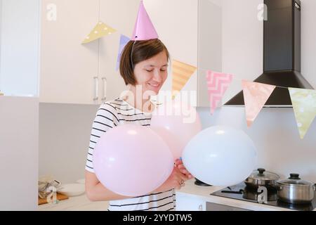 Die junge Frau feiert ihren Geburtstag zu Hause, umgeben von gemütlicher Atmosphäre und festlicher Dekoration. Sie genießt ihren besonderen Tag und bereitet sich auf den Urlaub vor Stockfoto