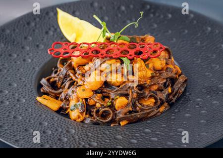 Ein köstlicher Teller schwarzer Linguine mit frischen Muscheln, Garnelen und Tintenfischen, kunstvoll mit einer reichhaltigen Sauce für ein Gourmet-Erlebnis mit Meeresfrüchten zubereitet Stockfoto