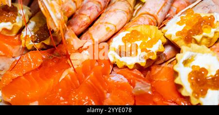 Auf einer lebendigen Platte mit Meeresfrüchten werden saftige Garnelen und frischer Lachs gepaart mit goldenem Kaviar präsentiert. Genießen Sie dieses Gourmet-Gericht, und genießen Sie den Genuss Stockfoto