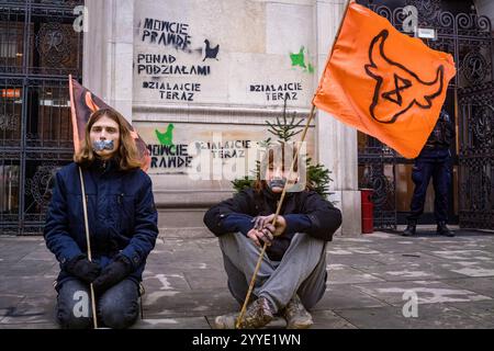 Die Demonstranten halten Fahnen, während sie während der Kundgebung vor dem Landwirtschaftsministerium sitzen. Aktivisten der Gruppe Animal Rebellion sprühten und malten ihre Forderungen an die Wände des Ministeriums für Landwirtschaft und ländliche Entwicklung in Warschau, befestigten ein Manifest am Tor und warteten dann mit geschlossenen Mündern still auf das Eintreffen der Polizei. Die polnische Tieraufstandsgruppe erklärte, dass alle Materialien, die für den Protest verwendet werden, leicht abwaschbar und nicht dauerhaft sind. Ziel der Aktion ist es, die Aufmerksamkeit auf das Leiden der Tiere und die Klimakosten solcher Industriezweige zu lenken Stockfoto