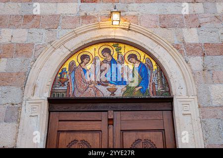 24. Oktober 2024, Budva, Montenegro: Mosaik der heiligen dreifaltigkeit über einer Holztür, symbolisiert Willkommen und spirituelle Ernährung Stockfoto