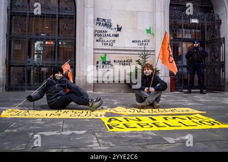 Demonstranten halten Fahnen, während sie während der Kundgebung vor ihrem Banner sitzen. Aktivisten der Gruppe Animal Rebellion sprühten und malten ihre Forderungen an die Wände des Ministeriums für Landwirtschaft und ländliche Entwicklung in Warschau, befestigten ein Manifest am Tor und warteten dann mit geschlossenen Mündern still auf das Eintreffen der Polizei. Die polnische Tieraufstandsgruppe erklärte, dass alle Materialien, die für den Protest verwendet werden, leicht abwaschbar und nicht dauerhaft sind. Ziel der Aktion ist es, die Aufmerksamkeit auf das Leiden der Tiere und die Klimakosten einer solchen industriellen Landwirtschaft zu lenken. (Phot Stockfoto