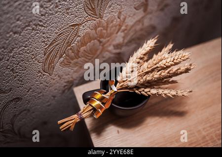 Elegantes Paket aus getrockneten Weizen in einer rustikalen Keramikvase auf Holzoberfläche. Stockfoto