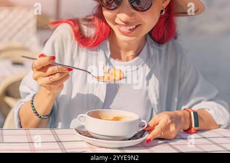 Glücklicher Tourist, der köstliche Meeresfrüchtesuppe in einem Restaurant im Freien mit wunderschönem Meerblick isst Stockfoto