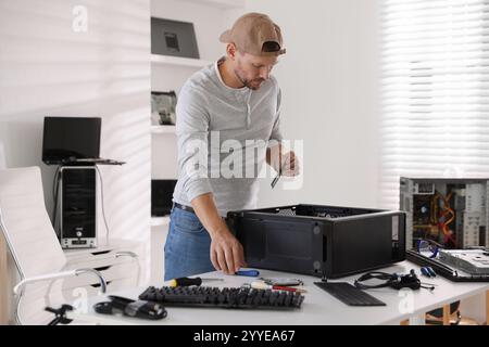 Mann, der einen neuen Computer am weißen Tisch zusammenbaut Stockfoto