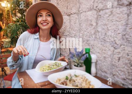 Junge Frau, die Pasta in einem typisch italienischen Restaurant isst und während ihrer Reise lokale Küche genießt Stockfoto