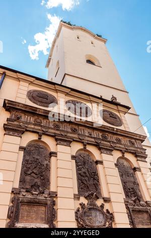 Ein hohes weißes Gebäude mit einem Uhrenturm und einem grünen Dach. Das Gebäude ist mit vielen Dekorationen versehen, darunter Statuen und eine große Uhr. Szene ist Stockfoto