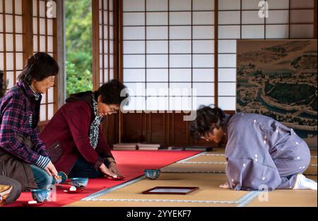 Frau im Kimono serviert japanischen Matcha-Grüntee in traditionellem Stil auf Tatami-Matten-Boden für Besucher im Genkyuen Hikone Castle Garden in Japan. Stockfoto