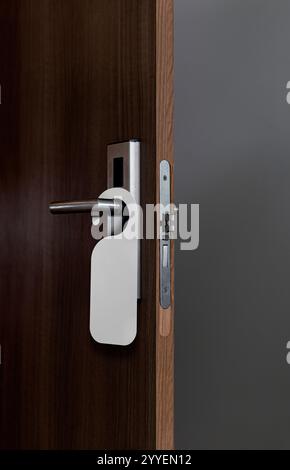 Holztür mit leerem Anhänger am Griff. Ideale Vorlage für Modell-Zeichen „nicht stören“. Stockfoto