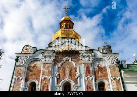 Eine Kirche mit einer goldenen Kuppel und einem goldenen Kreuz oben. Das Gebäude ist sehr alt und hat viele Details. Der Himmel ist blau und Wolken im B Stockfoto