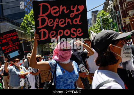 Melbourne, Australien. Dezember 2024. Ein Demonstrant hält während der Kundgebung ein Plakat. Demonstranten hielten eine Kundgebung in Melbourne CBD ab und forderten Sanktionen gegen Israel an Weihnachten, um die zionistische Aggression zu beenden und Menschenleben im Nahen Osten zu ehren. Quelle: SOPA Images Limited/Alamy Live News Stockfoto