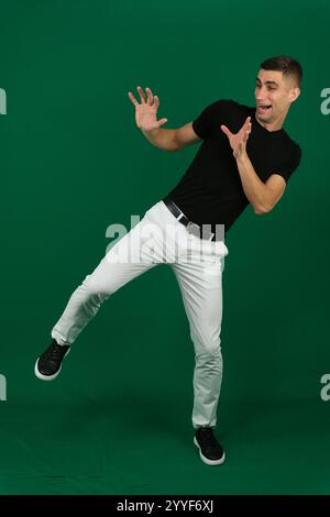 Mann in stilvollem Outfit, der auf blauem Hintergrund tanzt. Hochwertige Fotos Stockfoto