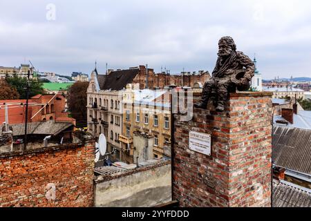 Eine Statue eines Mannes sitzt auf einem gemauerten Kamin in einer Stadt. Die Statue ist von Gebäuden und einem gemauerten Kamin umgeben. Die Szene ist ruhig und friedlich, mit Stockfoto