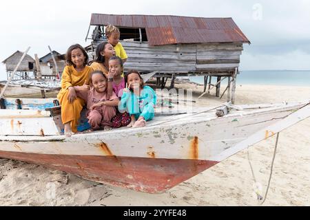 Bajau-Kinder spielen auf einem alten Holzboot in einem kleinen traditionellen bajau-Dorf auf einer kleinen Sandbank mitten im Meer, Häuser auf Stelzen, indonesien Stockfoto