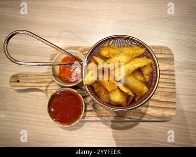Blick aus der Vogelperspektive auf gewürzte Pommes frites auf einem traditionellen Teller mit Chili- und Tomatensauce in der Nähe. Gewürzte Pommes frites ein sehr beliebter Snack für Teenager Stockfoto