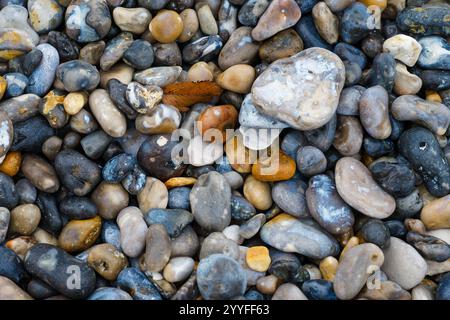 Farbenfrohe Kieselsteine, die entlang des Flusses verstreut sind, mit verschiedenen Formen und Größen im Sonnenlicht an einem ruhigen Nachmittag Stockfoto