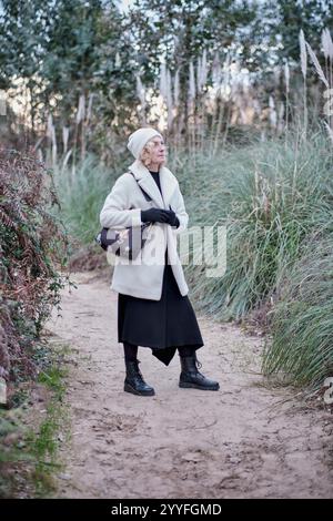 Ältere Frau in Winterkleidung, die an einem sonnigen Wintertag in einem Park in kantabrien, spanien, spaziert Stockfoto