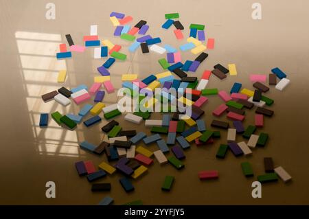 Verstreute bunte Blöcke auf dem Boden, in Sonnenlicht getaucht, das durch ein Fenster strömt. Ein verspieltes Chaos aus Farben und Schatten. Stockfoto