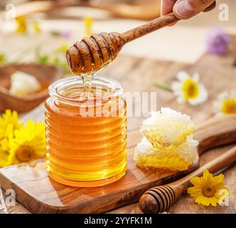 Natürlicher Bio-Honig im Glasgefäß, Honiglöffel und Waben sind in der Nähe. Natürlicher Lebensmittelhintergrund. Stockfoto