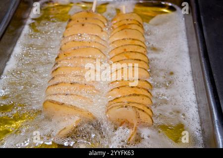 Knusprige Spiralkartoffeln, die in heißem Öl gebraten werden. Perfekt für Food-Blogs, Speisekarten und Rezept-Websites. Stockfoto
