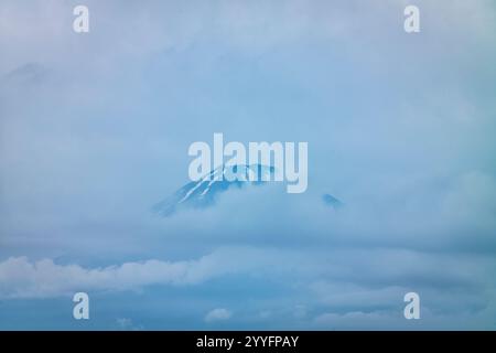 Panoramabild des Mount Fuji in Japan, aufgenommen an einem bewölkten Tag mit stimmungsvollen Wolken, die in der Nähe des Gipfels schweben. Stockfoto