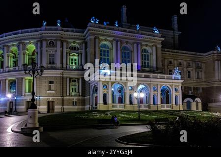 Ein großes Gebäude mit vielen Fenstern und einer Statue davor. Das Gebäude ist nachts beleuchtet Stockfoto