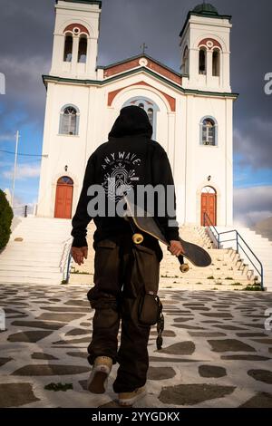 Junge Griechen üben Skateboard vor der Faneromeni (Panagia) orthodoxen christlichen Kirche in Naoussa auf der Insel Paros in Griechenland Stockfoto