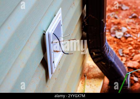 Mechaniker, der elektrische Kabel an der Wandsteckdose hält Stockfoto