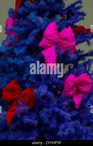 Blauer künstlicher Weihnachtsbaum mit großen rosafarbenen Bögen. Nahaufnahme. Stockfoto