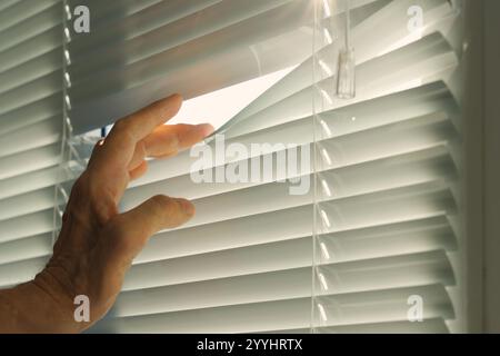Hand, Mann, der durch Fensterläden guckt. Stockfoto
